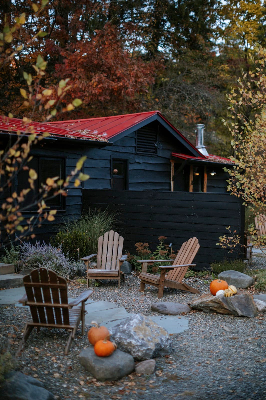 Pumpkins and Adirondack chairs outside The Leeway's black cabins on an October evening